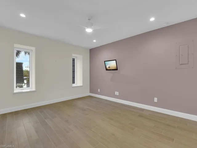 Empty room with electric panel, ceiling fan, and light hardwood / wood-style flooring