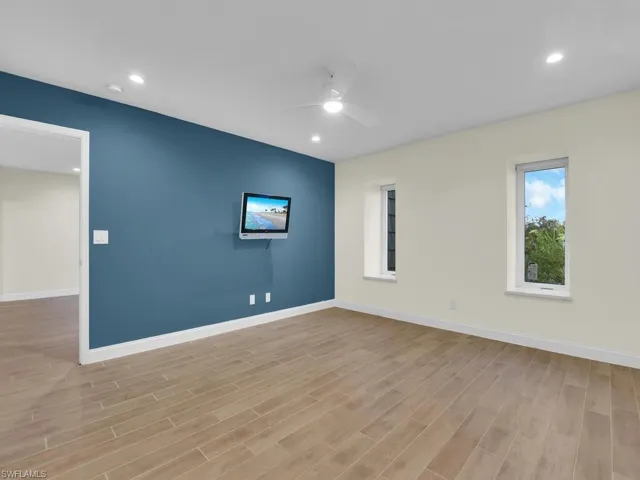 Primary bedroom with ceiling fan and light hardwood / wood-style flooring
