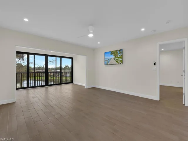 Living room featuring ceiling fan, a water view, and wood-type flooring