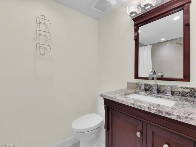 Bathroom featuring walk in shower, vanity, and toilet