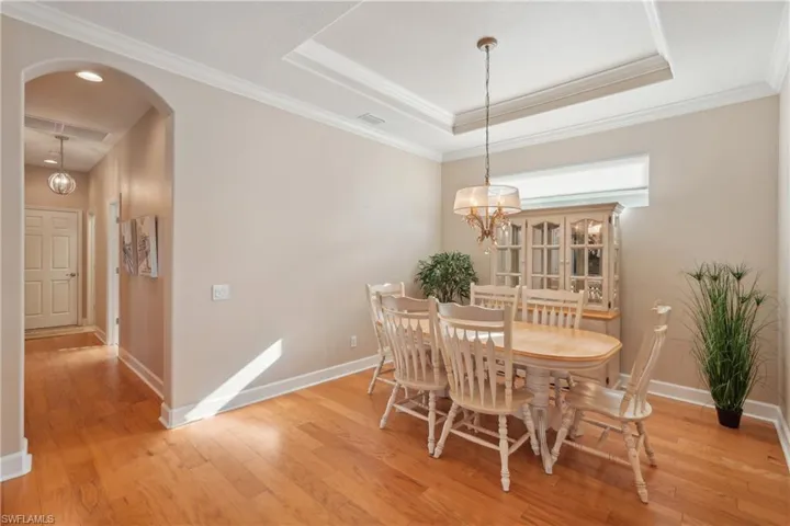 Dining area featuring light hardwood / wood-style floors, a raised ceiling, a chandelier, and ornamental molding