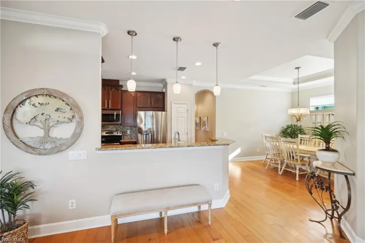 Kitchen featuring tasteful backsplash, light hardwood / wood-style flooring, stainless steel appliances, and light stone countertops