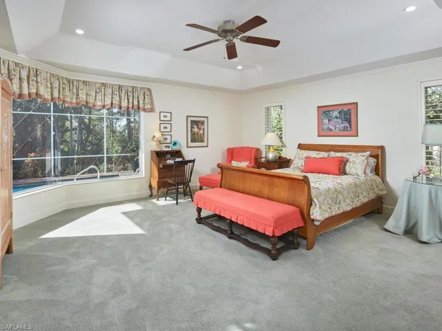 Large primary bedroom with volume ceiling and a view of the pool.