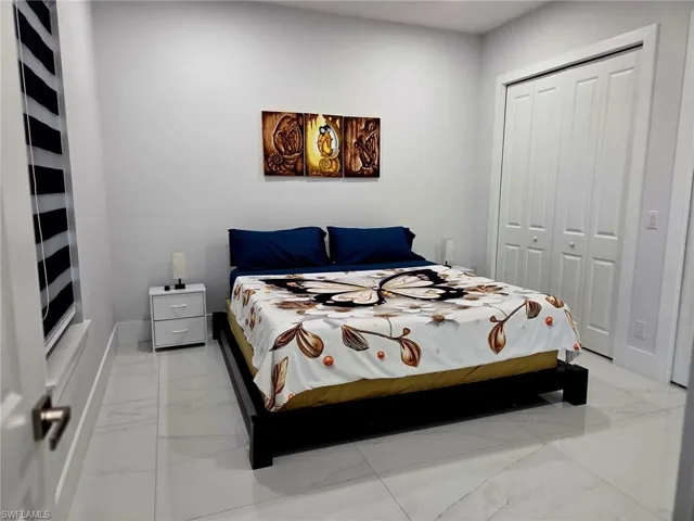 Bedroom featuring a closet and light marble finish flooring