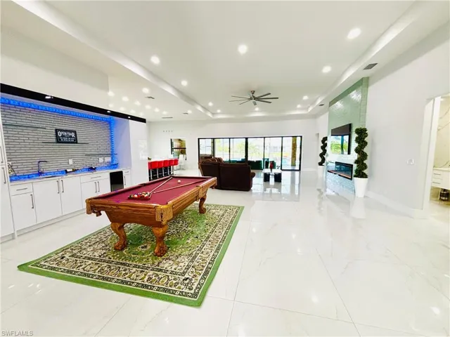 Game room with ceiling fan, billiards table, a raised ceiling, recessed lighting, and bar area