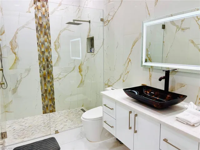 Bathroom with a marble finish shower and vanity