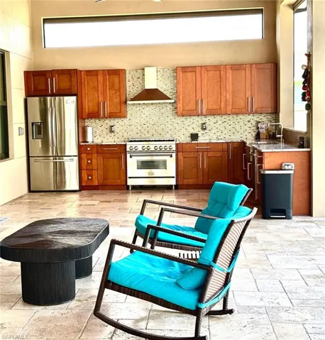 Kitchen with stone tile floors, stainless steel appliances, wood finish cabinets, light stone counters, and tasteful backsplash