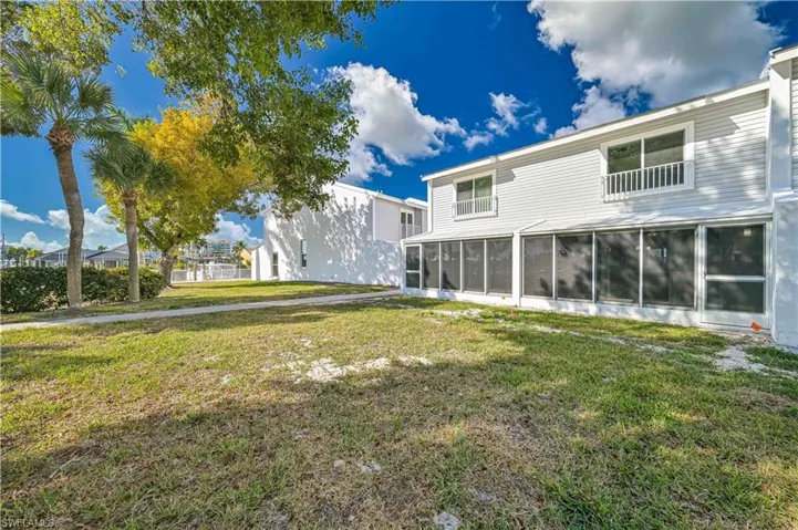 Rear view of property featuring a lawn and a sunroom