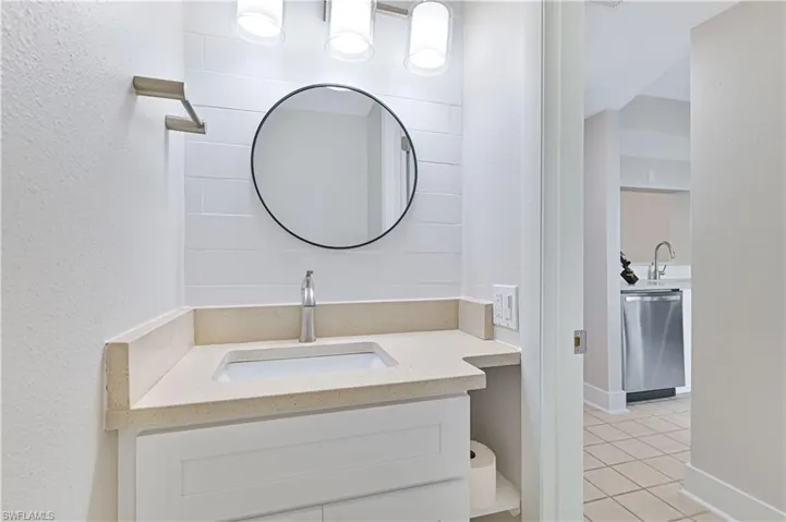 Bathroom with vanity, a textured wall, and light tile patterned floors