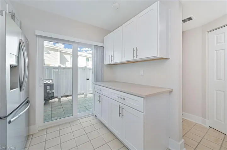Kitchen featuring stainless steel refrigerator with ice dispenser, light countertops, white cabinetry, and light tile patterned floors