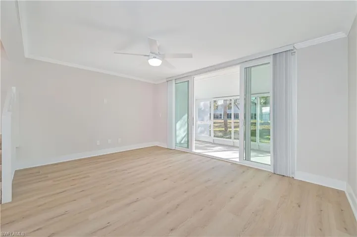 Empty room featuring light wood-style flooring, crown molding, and a ceiling fan