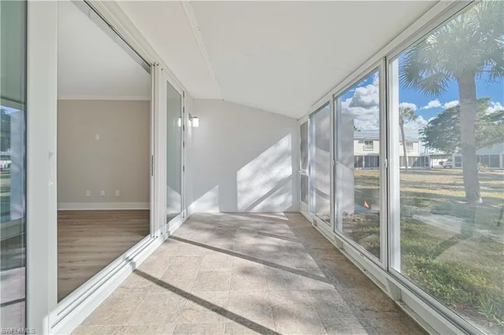 Unfurnished sunroom featuring stone tile floors and vaulted ceiling