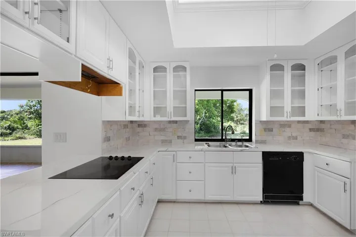 Kitchen with black appliances, healthy amount of natural light, and light stone countertops