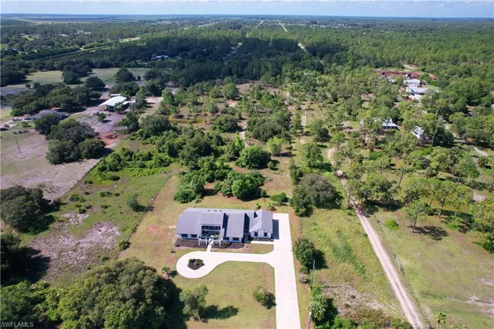 Aerial view of property and surrounding area with a forest