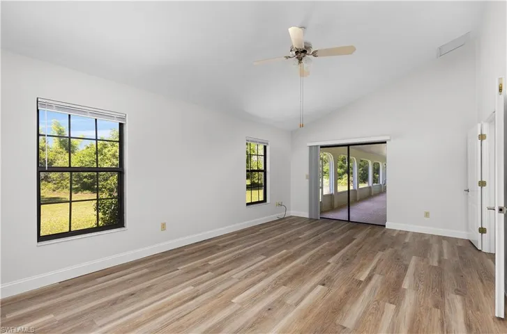 Unfurnished room with healthy amount of natural light, light wood-style flooring, a ceiling fan, and high vaulted ceiling