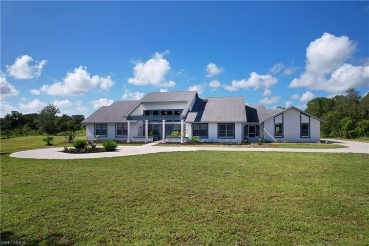 View of front of property featuring a front lawn, curved driveway, and stucco siding
