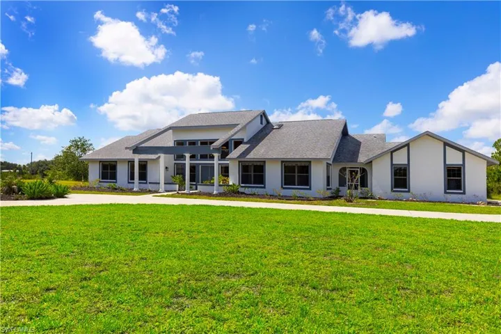 View of front of house featuring stucco siding, a front lawn, and roof with shingles
