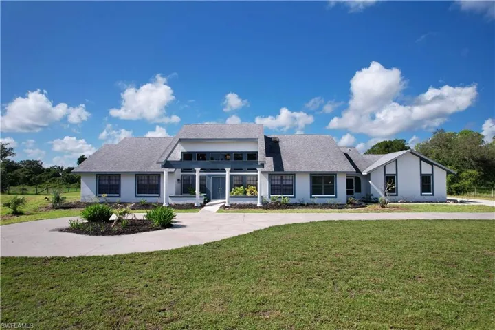 View of front of home featuring a front yard, curved driveway, and stucco siding