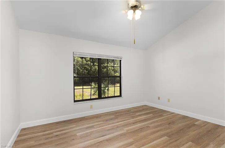 Empty room featuring light wood-type flooring, ceiling fan, and vaulted ceiling