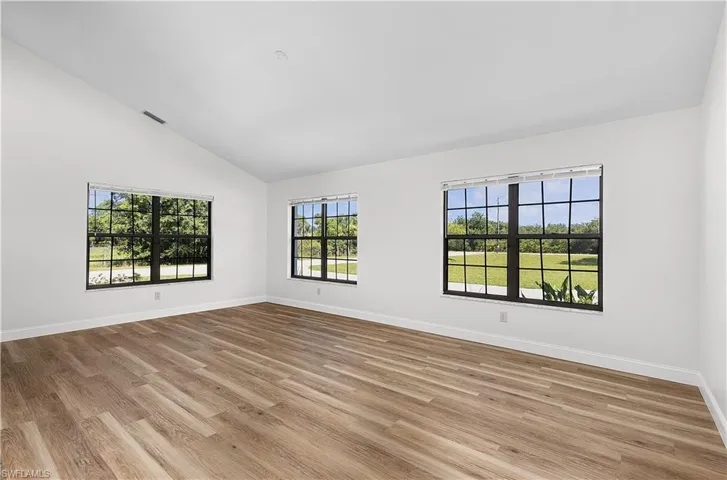 Unfurnished room featuring light wood-type flooring and high vaulted ceiling