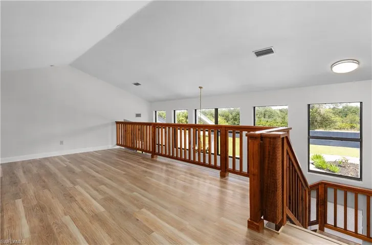 Bonus room with light wood-style flooring and vaulted ceiling