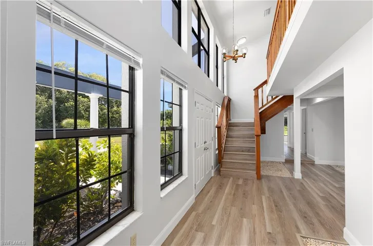 Entrance foyer with a chandelier, light wood finished floors, stairway, and a towering ceiling