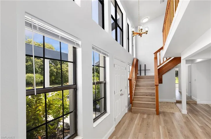 Entryway with a high ceiling, a chandelier, light wood-style floors, and stairway