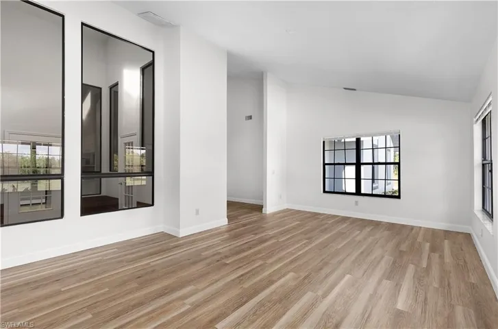 Spare room featuring wood finished floors and vaulted ceiling