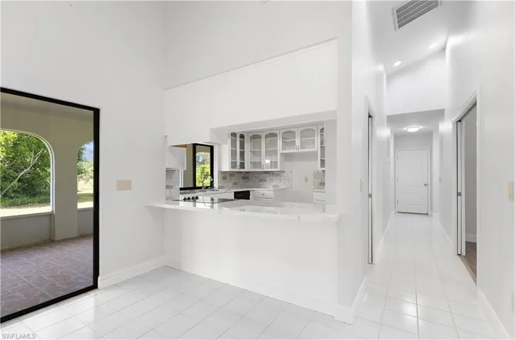 Kitchen featuring a high ceiling, light countertops, light tile patterned floors, and healthy amount of natural light