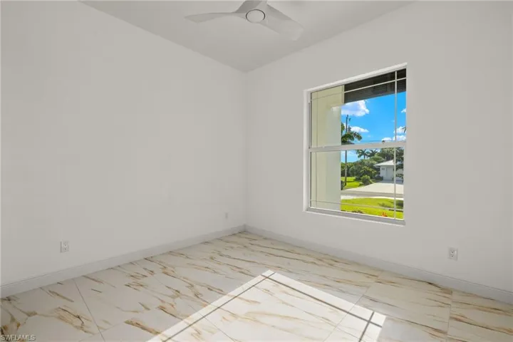 Unfurnished room with light marble finish floors and a ceiling fan