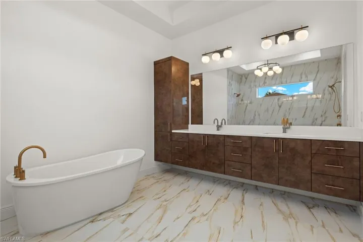 Bathroom with double vanity, light marble finish floors, a freestanding tub, and a marble finish shower