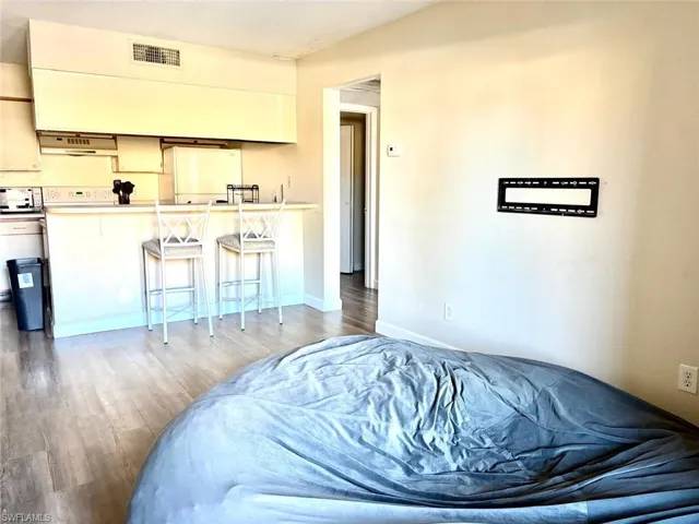 Bedroom with light wood-style floors, freestanding refrigerator, and a closet