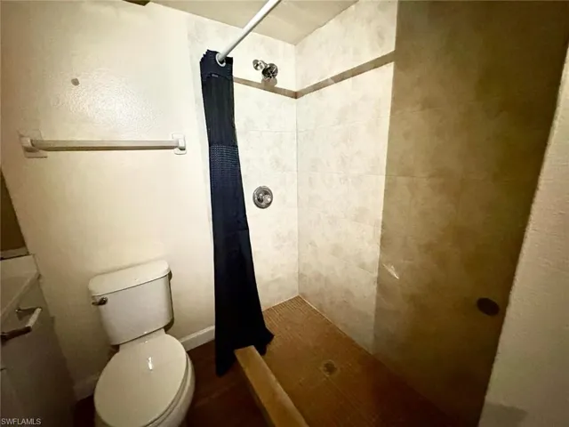 Full bath featuring a shower stall and toilet