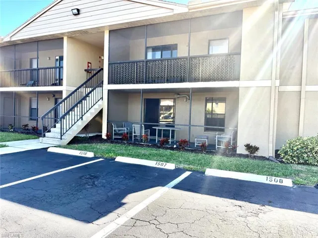 View of property with stairs and uncovered parking