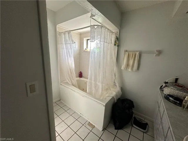 Bathroom with tile floors and shower / tub combo with curtain
