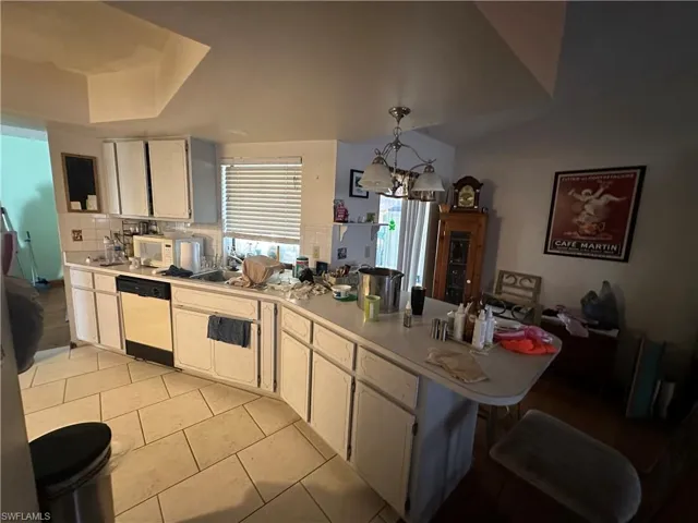 Kitchen featuring decorative light fixtures, a chandelier, white cabinets, white appliances, and light tile floors
