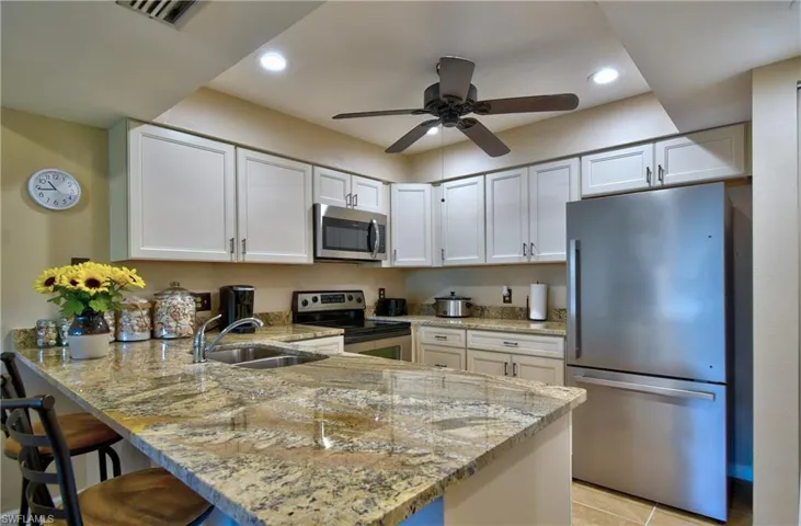 Kitchen featuring white cabinets, light stone countertops, appliances with stainless steel finishes, and kitchen peninsula