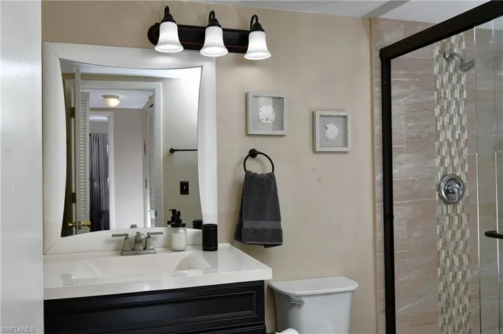 Bathroom with vanity, toilet, and an enclosed shower