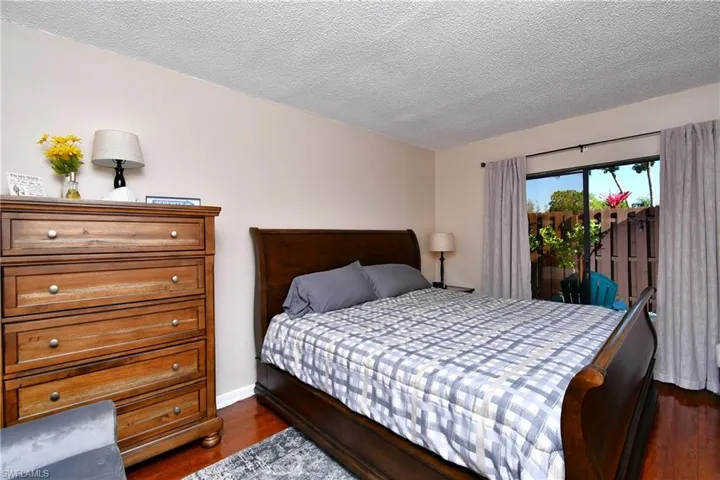Bedroom with dark wood-type flooring, a textured ceiling, and access to outside
