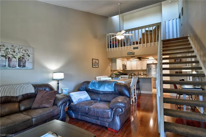 Living room featuring ceiling fan, dark hardwood / wood-style floors, and a high ceiling
