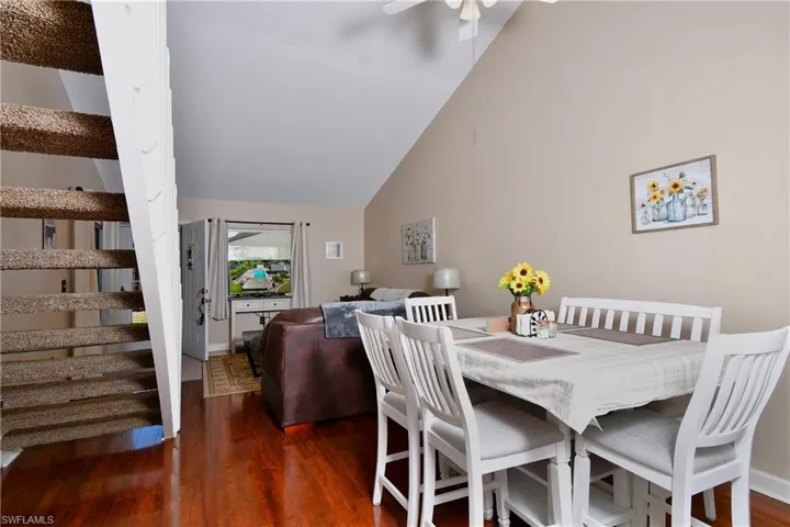 Dining room with high vaulted ceiling, ceiling fan, and dark hardwood / wood-style flooring