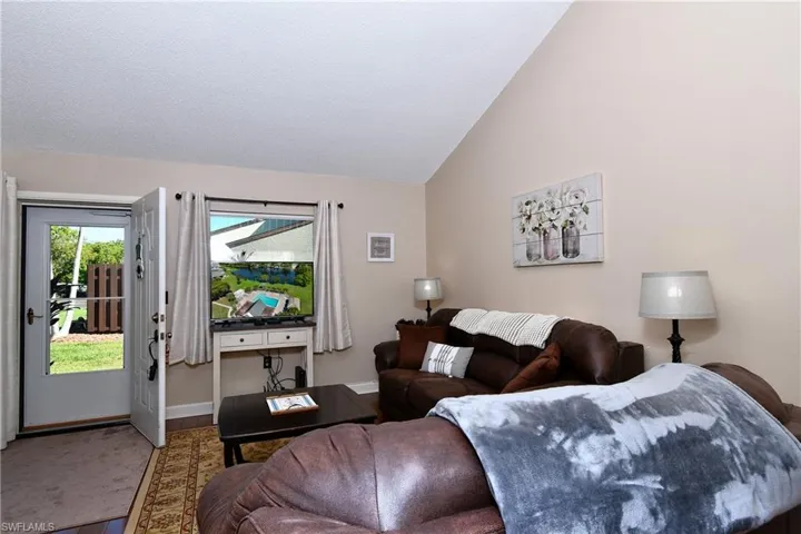 Carpeted living room featuring high vaulted ceiling