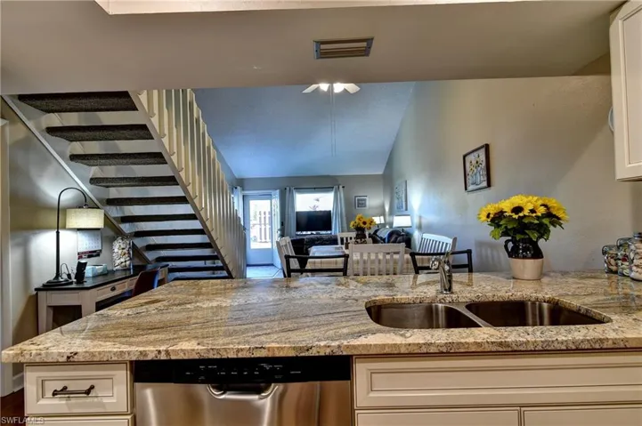 Kitchen featuring sink, white cabinetry, dishwasher, and light stone counters