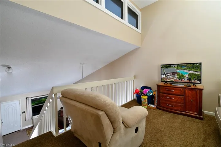 Carpeted living room featuring high vaulted ceiling