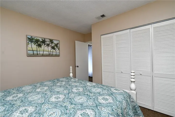 Carpeted bedroom featuring a textured ceiling and a closet