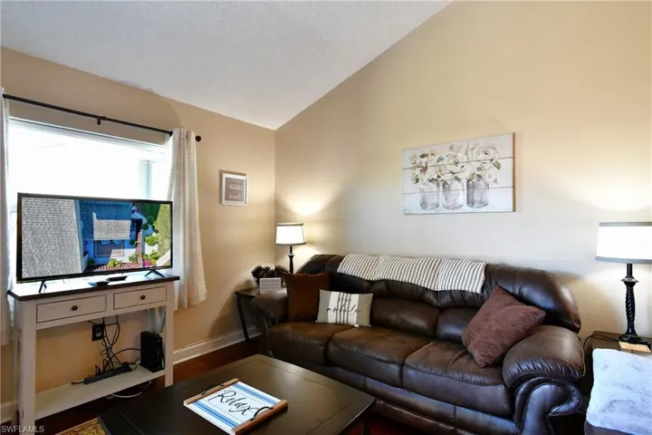 Living room with wood-type flooring, lofted ceiling, and a textured ceiling