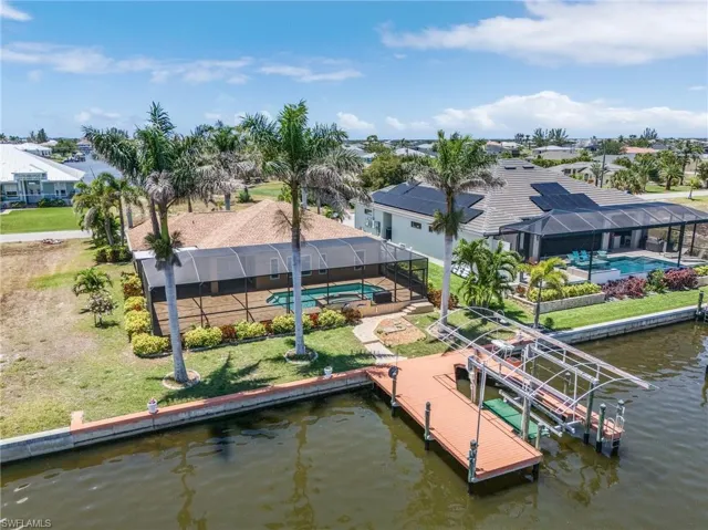 Dock area with an outdoor pool, boat lift, a water view, a residential view, and a lanai