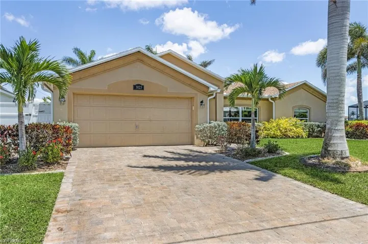 View of front of house with stucco siding, decorative driveway, an attached garage, and a front yard