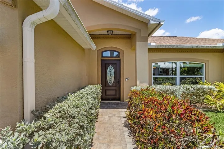 Property entrance with stucco siding and roof with shingles