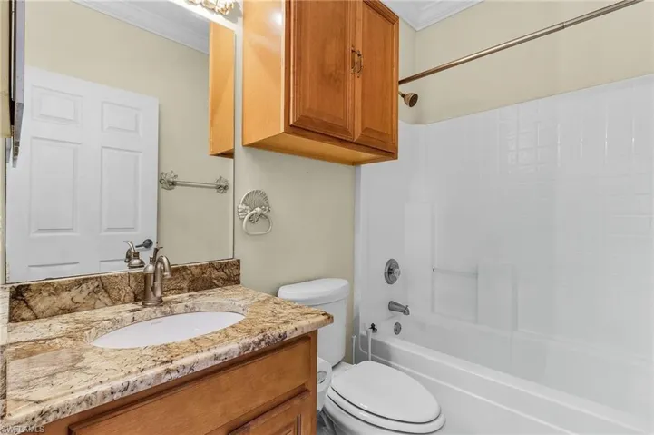 Bathroom featuring ornamental molding, toilet, vanity, and tub / shower combination
